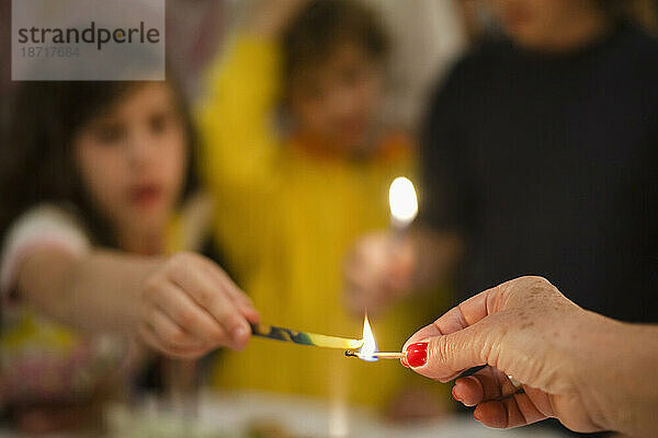 Eine Person zündet bei einer Chanukka in Buenos Aires  Argentinien  eine Kerze an  die ein Kind hält.