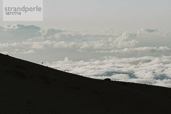 Rückansicht eines hölzernen Wegweisers am Berghang über Wolken