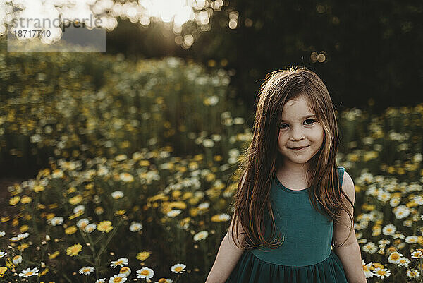 Porträt eines kleinen Mädchens in einem von hinten beleuchteten Blumenfeld im Frühling