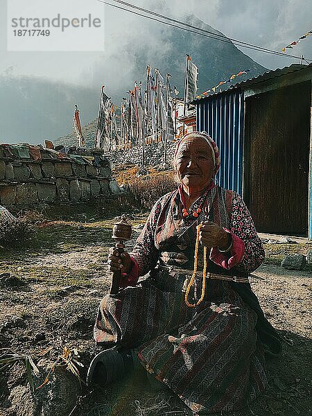 Ältere Frau in bewölkten Bergen mit Gebetsperlen