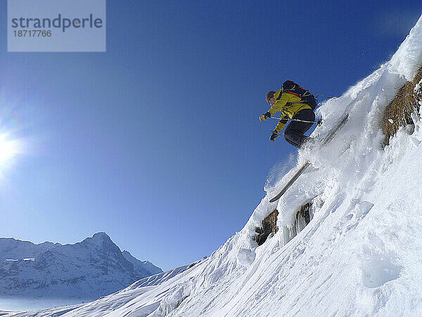 Ein Mann fährt im Skigebiet Grindelwald im Schweizer Berner Oberland eine Piste hinunter. (blauer Himmel  frisches Sonnenlicht)