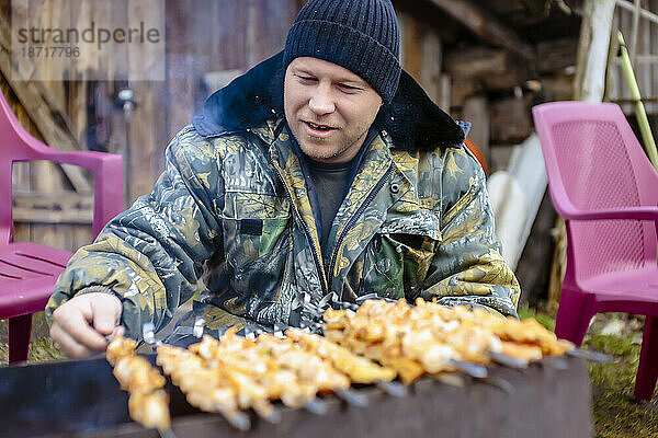 Vorderansicht eines Mannes  der Fleischspieße auf dem Grill kocht  Tichwin  Sankt Petersburg  Russland