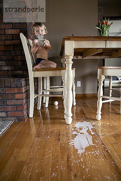 Kleines Mädchen verschüttet versehentlich Getränk vom Tisch auf den Boden