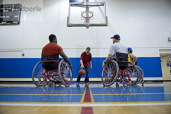 Ein Trainer demonstriert den Ballhandling beim Rollstuhlbasketballtraining.