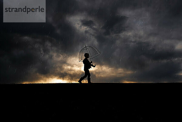 Silhouette eines 5-jährigen Jungen  der im Regen läuft