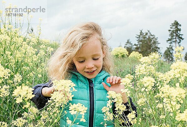 Junges Mädchen  das lächelnd durch ein Feld mit gelben Blumen geht