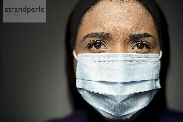 Studio-Nahaufnahmeporträt einer 21-jährigen afroamerikanischen Frau  die eine medizinische Maske trägt.