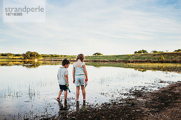 Junge und Mädchen suchen mit Netzen im See nach Fischen