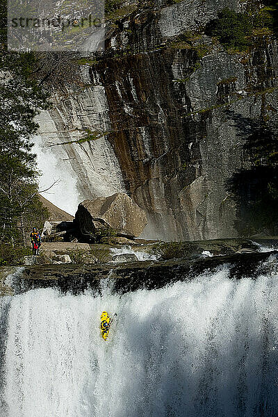 Kajakfahrer lässt einen großen Wasserfall in einer steilen Granitschlucht fallen.