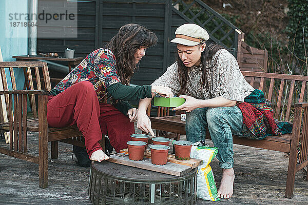 Queeres weibliches Paar pflanzt im Frühling Setzlinge an Deck