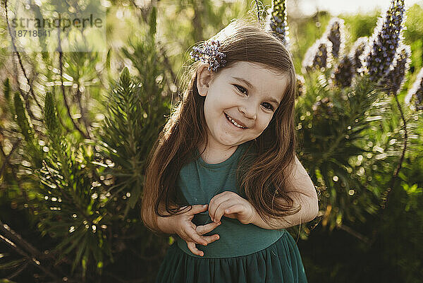 Porträt eines kleinen Mädchens mit Blumen im Haar  das auf der Wiese lächelt