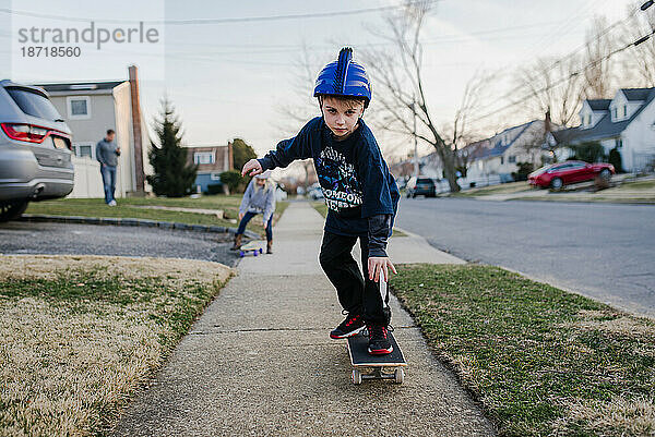 Junge auf Gehweg auf Skateboard mit Helm