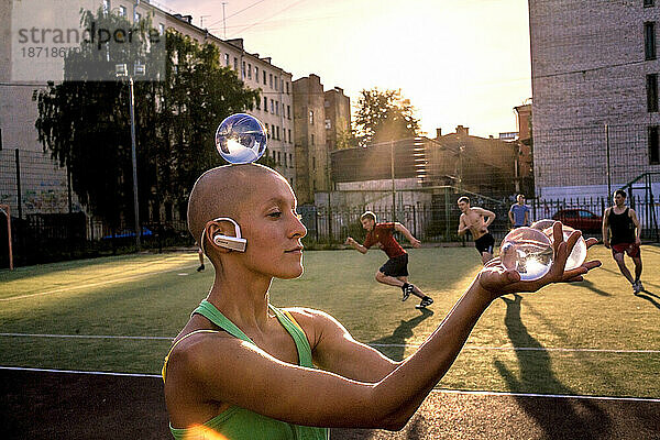 Glatze Frau jongliert mit Kristallkugel im Park