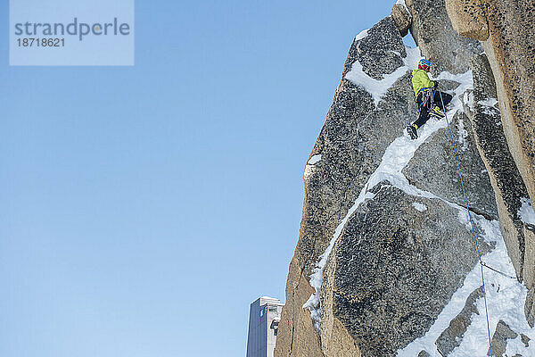 Ein Alpinist läuft auf der Aiguille du Midi durch steiles gemischtes Gelände