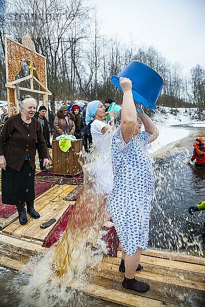 Frauen gießen während der Weihnachtstradition in Russland kaltes Wasser ein