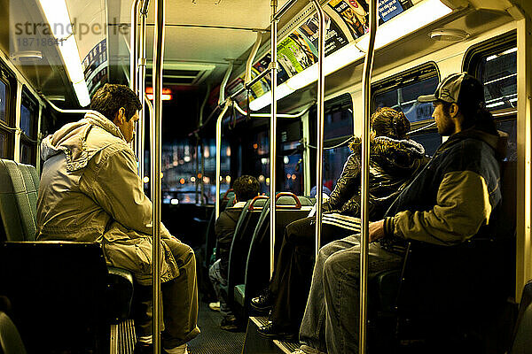 Mehrere Passagiere sitzen in einem Bus in Seattle  Washington  während der Bus in der Abenddämmerung durch den Verkehr fährt.