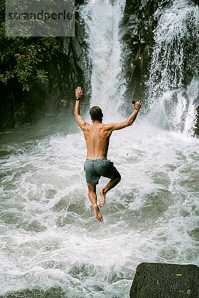 Mann springt von einem Wasserfall. Bali.
