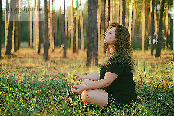 Junge Frau praktiziert Yoga bei Sonnenaufgang