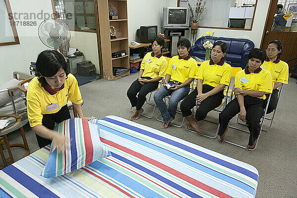 Eine Gruppe von Auszubildenden wird beim Bettenmachen an der Maid School in Singapur angeleitet.