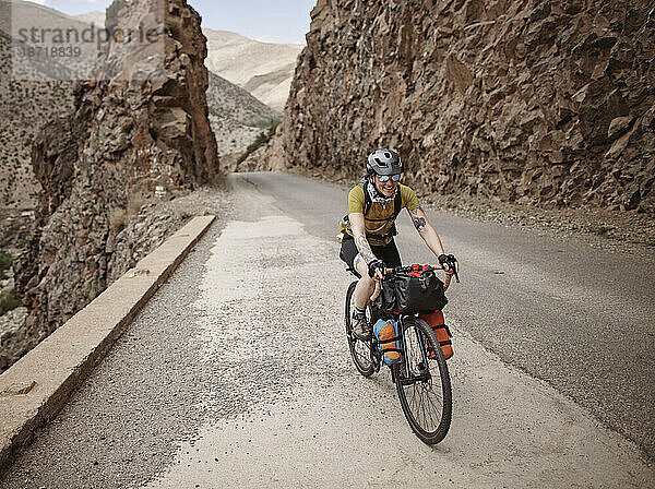 Eine Bikepackerin fährt eine Bergstraße im Atlasgebirge entlang