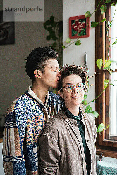 Sanfter romantischer Moment eines queeren Paares zu Hause mit Pflanzen