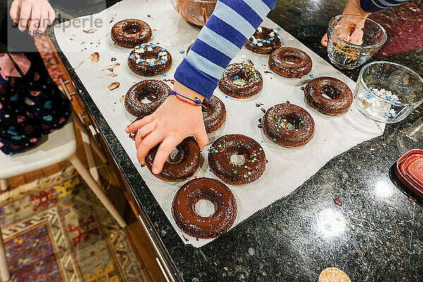 Draufsicht auf Kinder  die zu Hause auf der Küchentheke Donuts backen