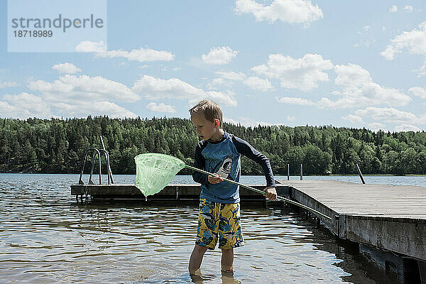 Junge fischt am Strand mit einem Netz