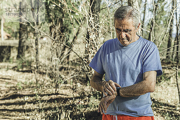 Alter Jogger schaut nach dem Laufen auf seine Armbanduhr