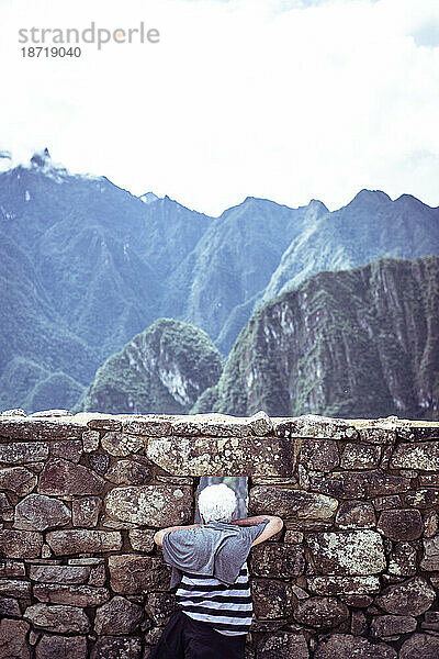 Rentnerin schaut aus dem Dorffenster in den Ruinen der Stadt Machu Picchu