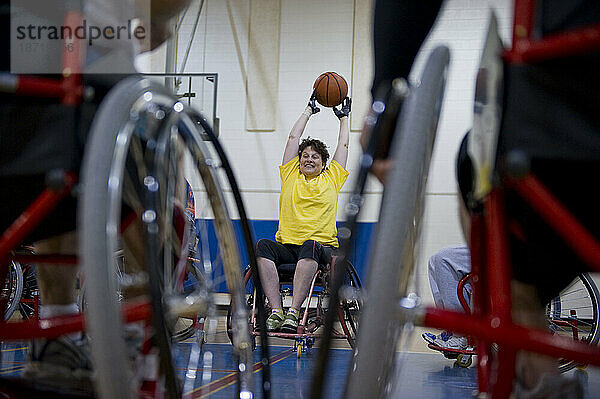 Eine Frau aus der Rollstuhlbasketballmannschaft fängt beim Training einen wilden Ball.