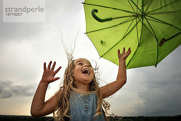 Kleines Mädchen mit Regenschirm und großem Lächeln