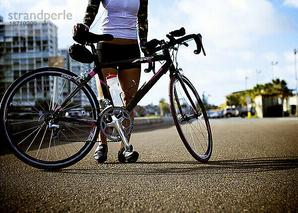 Junge Frau hält ihr Fahrrad.
