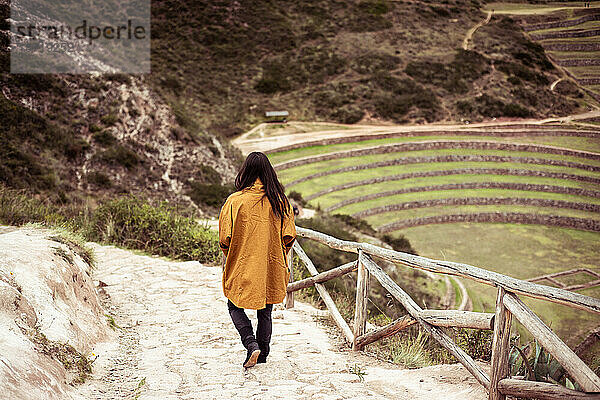 Person in Jacke geht Stufen einer archäologischen Inka-Ruinenstätte hinunter