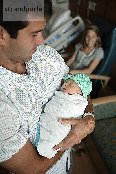 Ein Vater hält seine neugeborene Tochter am Tag nach ihrer Geburt.