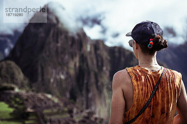 Frau mit Mütze blickt auf Machu Picchu und die Berge