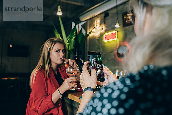 Zwei Freundinnen machen ein Foto in einer Cocktailbar.