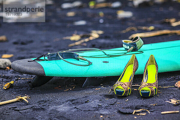 High Heels sitzen vor dem Surfbrett am Strand.