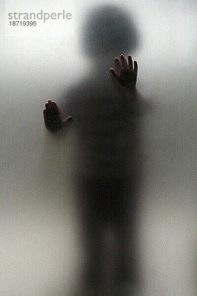 Ein Kind drückt seine Hände gegen eine Glastür.