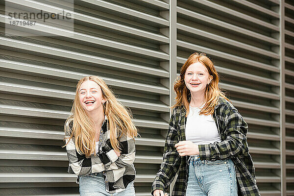 Zwei lachende Teenager-Mädchen gehen zusammen.