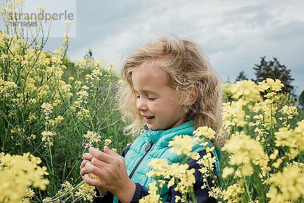 Ein junges Mädchen saß lächelnd in einem Feld mit gelben Blumen