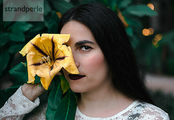 Junge Frau mit einer gelben Blume im Gesicht