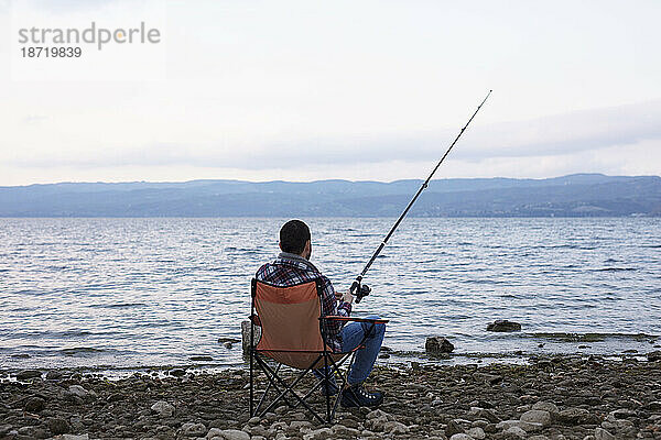 Mann im Lager in der Nähe des Sees  versucht zu angeln