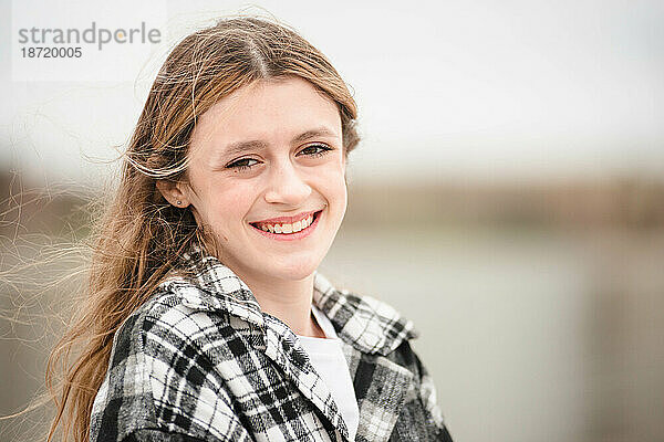 Schönes Teenager-Mädchen mit braunen Augen  das draußen lächelt.