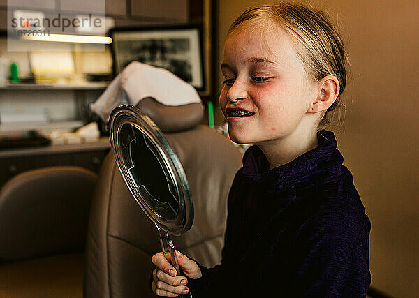 Junge Zahnpatientin freut sich über ihr neues Lächeln mit Zahnspange