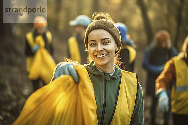 Freiwilliges Mädchen reinigt Wälder mit einem Müllsack und blickt in die Kamera.
