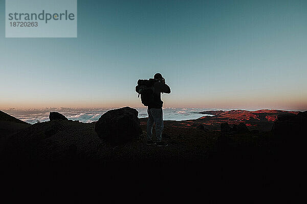 Ein Wanderer macht ein Foto bei Sonnenuntergang in El Teide  Teneriffa