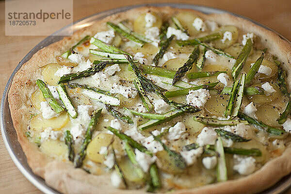 Auf einer Holztheke in Seattle  Washington  steht eine Pizza mit Bio-Spargel  Jungkartoffeln und Paprika.