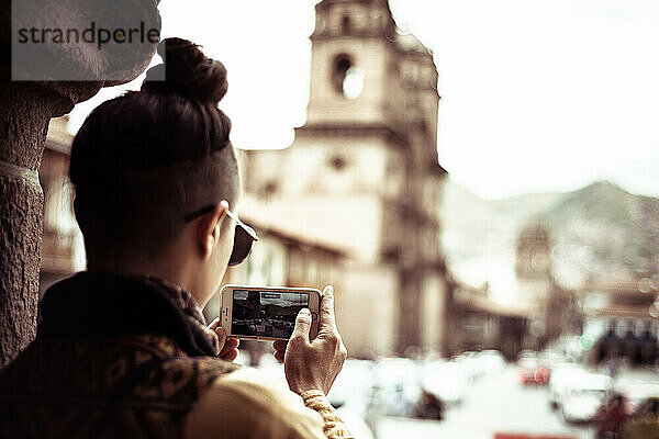 Androgyner Reisender macht mit dem Telefon ein Foto vom Kirchplatz
