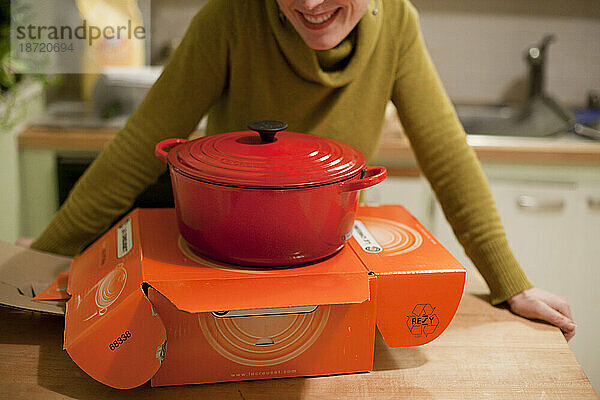 Eine Frau lächelt  nachdem sie einen Le Creuset Dutch Oven als Geschenk in ihrer heimischen Küche in Seattle  Washington  geöffnet hat.