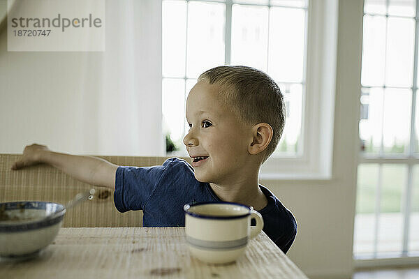 Porträt eines kleinen Jungen  der am Frühstückstisch spielt